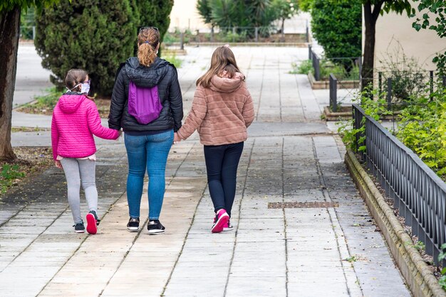 Photo rear view of mother with daughters walking on footpath