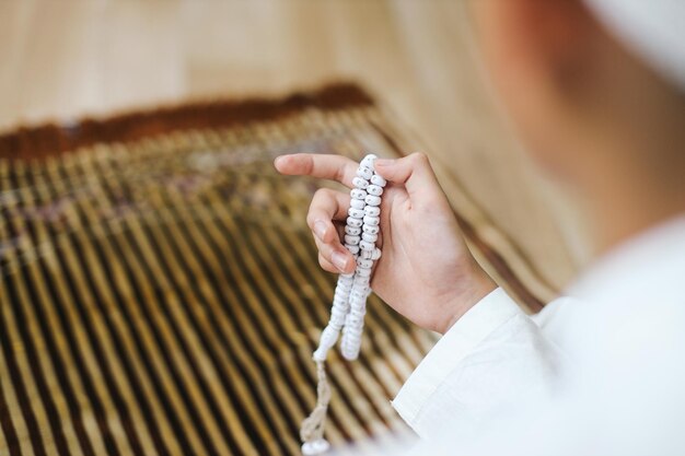 Photo rear view of muslim boys hand holding rosary prayer beads