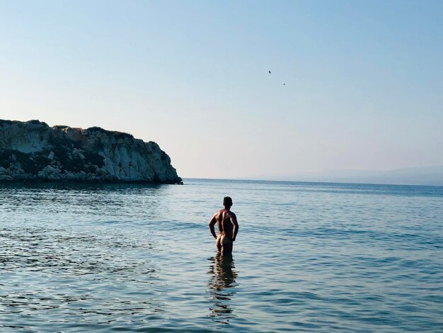 Foto vista posteriore di un uomo nudo in piedi in mare