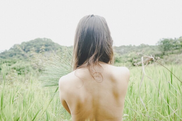 Rear view of naked woman on field against sky