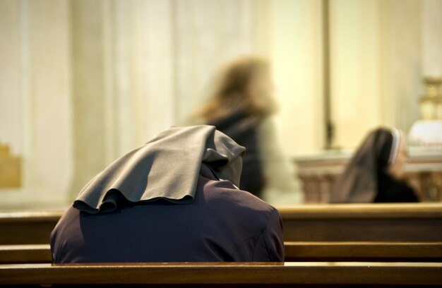 Photo rear view of nun praying at church