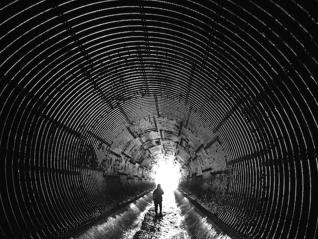 Фото Задний вид женщины, идущей по дренажному туннелю