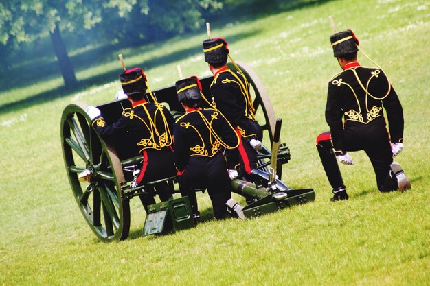 写真 芝生の畑で金属の車輪を持った軍隊の兵士の後ろの景色