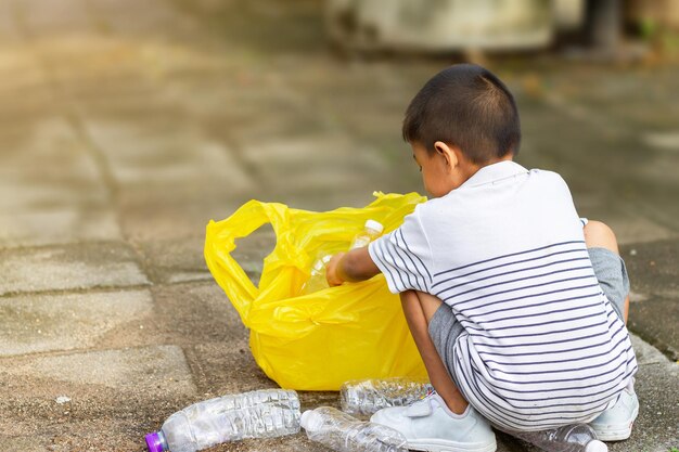 写真 外に座っている少年がプラスチック袋を見ている後ろの景色