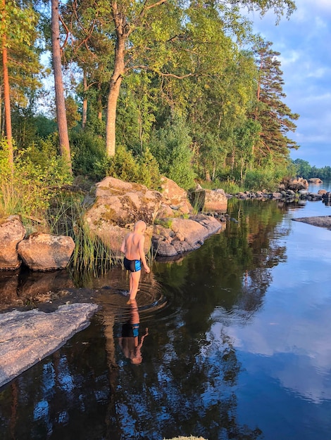 Фото Задний вид мальчика, идущего по озеру рядом с камнями