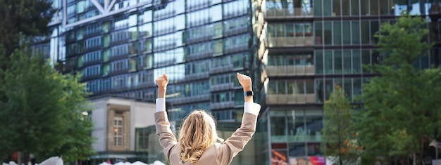 写真 手を上げて勝利を収めて目標を達成したことを祝う企業の女性弁護士の背面図または