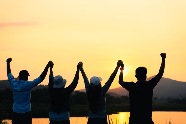 写真 夕暮れの空に向かって手をつないでいる友達の後ろの景色