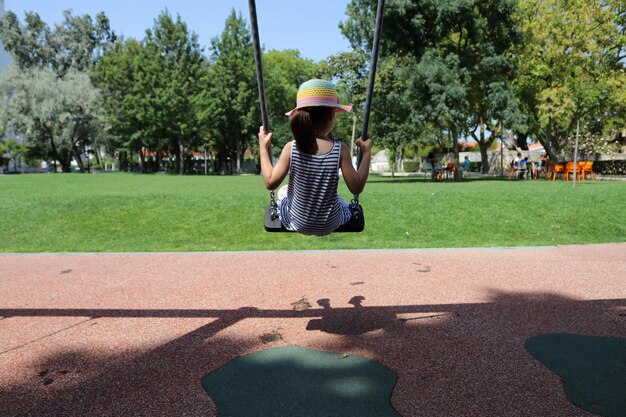 写真 遊び場でスイングをしている女の子の後ろの景色