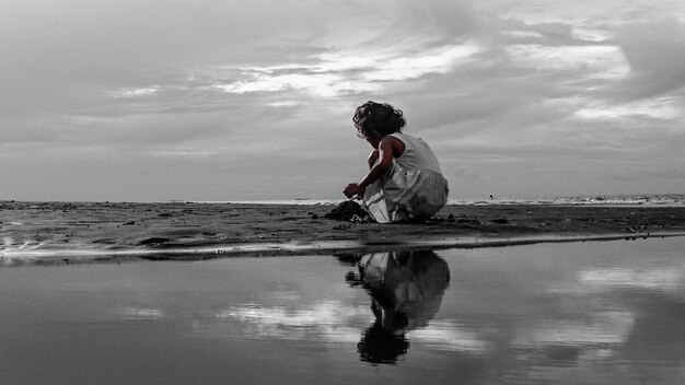 写真 空の向こうのビーチで海岸で遊んでいる女の子の後ろの景色