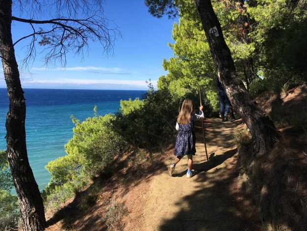 写真 海の向こうの小道を歩いている女の子の後ろの景色