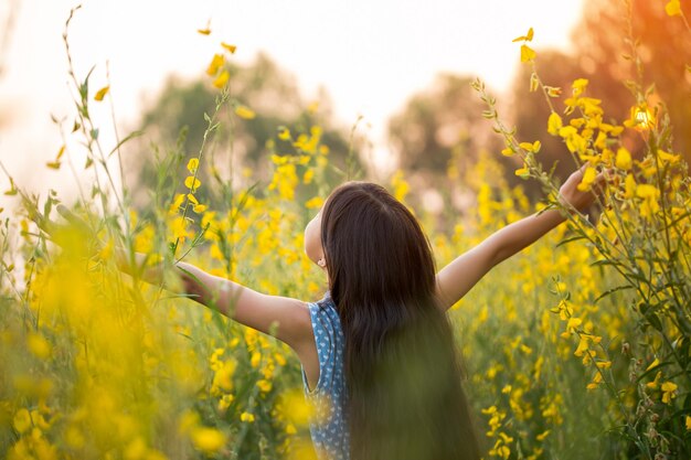 写真 フィールドに立っている腕を伸ばした女の子の後ろの景色