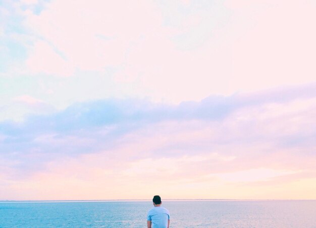 写真 夕暮れの際に海を背景にした男の後ろの景色