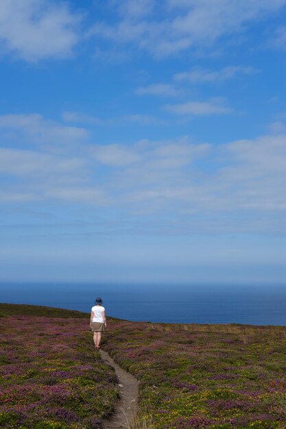 写真 空を背景に海沿いの男の後姿