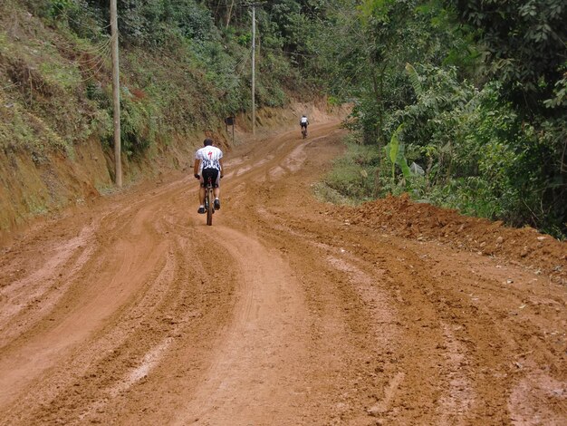 写真 泥道で自転車に乗っている男の後ろの景色