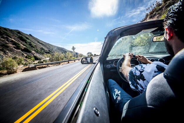 写真 道路で車を運転している男の後ろの景色