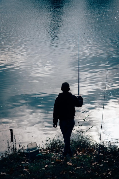 写真 湖で釣りをしている男の後ろの景色