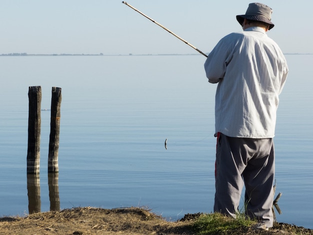 写真 海で釣りをしている男の後ろの景色