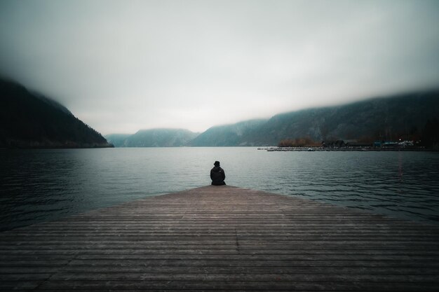 写真 空に照らされた湖を眺める男の後ろの景色