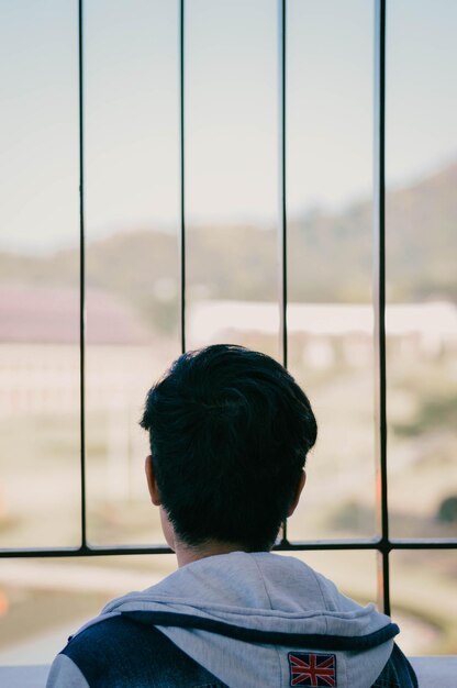 写真 窓から見る男の後ろの景色