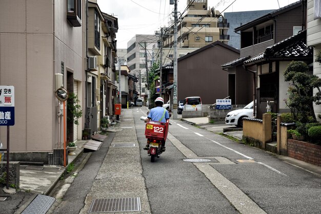 写真 街の道路でモータースクーターに乗っている男の後ろの景色