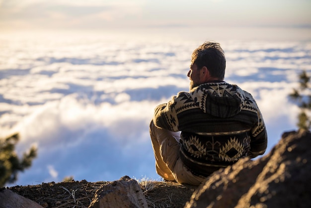 写真 海の向こうの岩の上に座っている男の後ろの景色