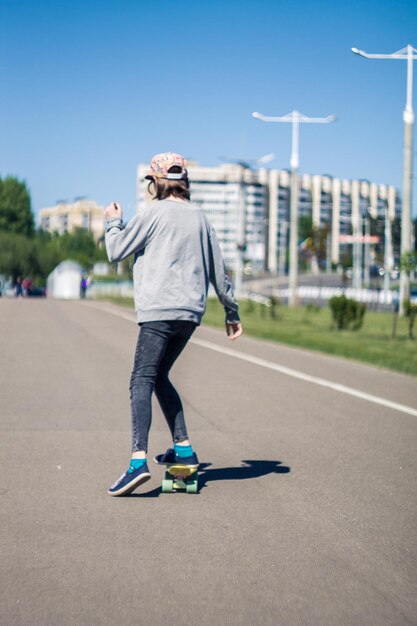 写真 晴れた日,澄んだ青い空の向こうの道路でスケートボードをしている男の後ろの景色