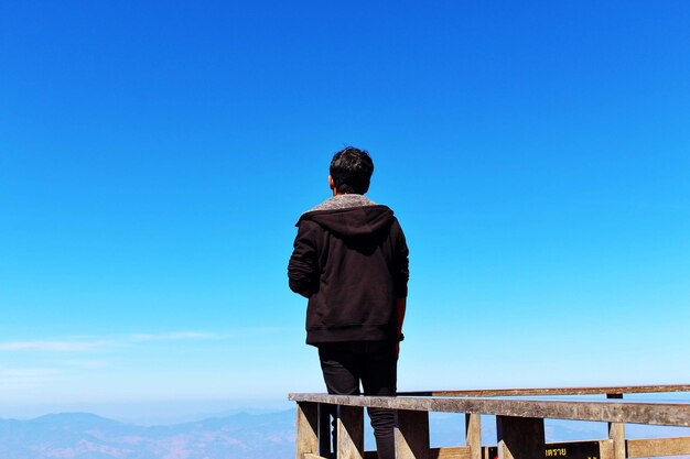 写真 澄んだ青い空に立っている男の後ろの景色