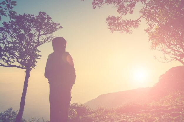 写真 夕暮れ の 時 に 空 に 向かっ て 立っ て いる 人 の 後ろ の 景色