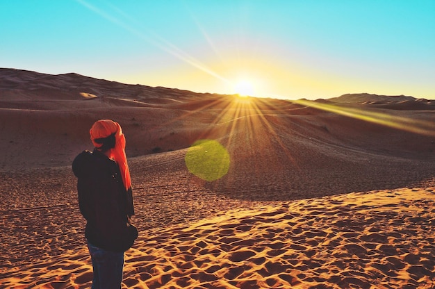 写真 夕暮れの空に逆らって砂漠に立っている男の後ろの景色
