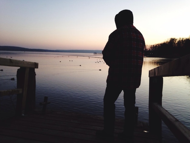 写真 空に向かって湖に立っている男の後ろの景色
