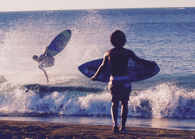 写真 浜辺に立っている男の後ろの景色