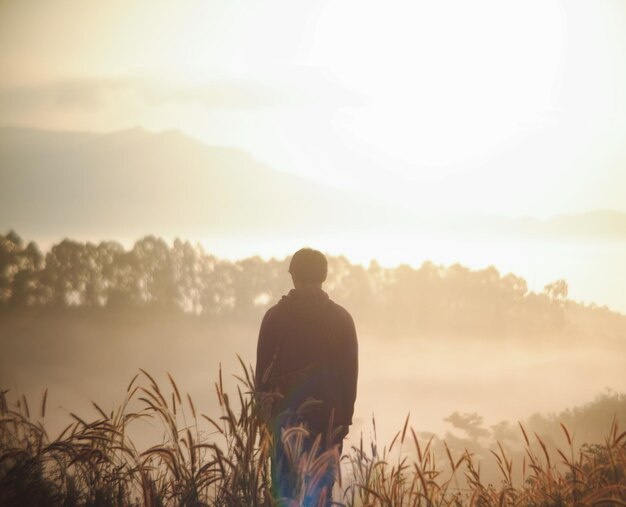 写真 夕暮れの空を背景に陸上に立っている男の後ろの景色