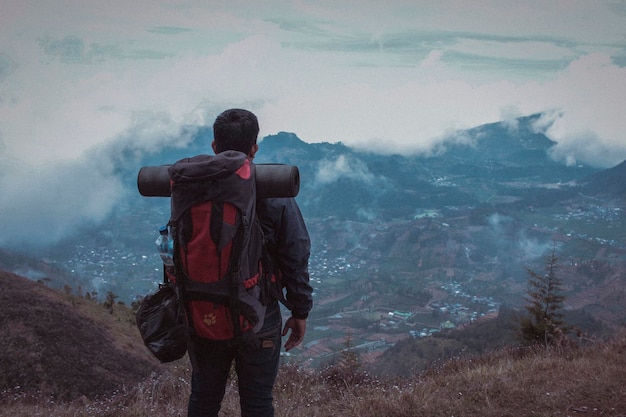 写真 山の上に立っている男の後ろの景色