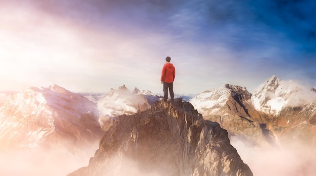 写真 天空を背景に岩の上に立っている男の後ろの景色