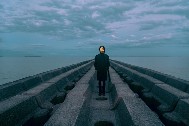 写真 海と空を背景に岩の上に立っている男の後ろの景色