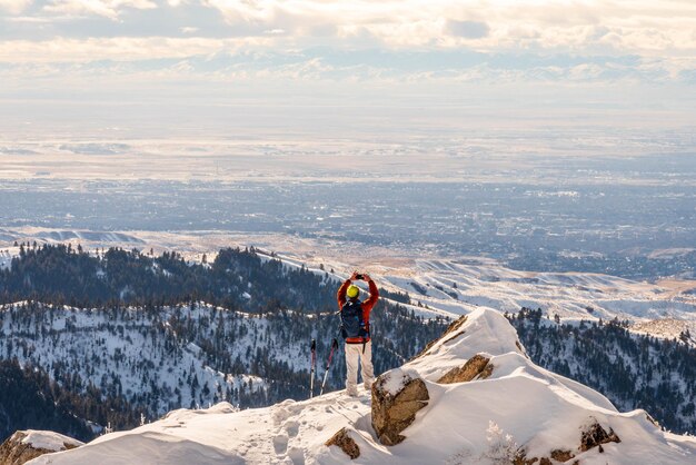 写真 空に照らして雪に覆われた山の上に立っている男の後ろの景色