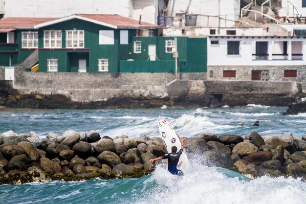 写真 海でサーフボードをしている男の後ろの景色