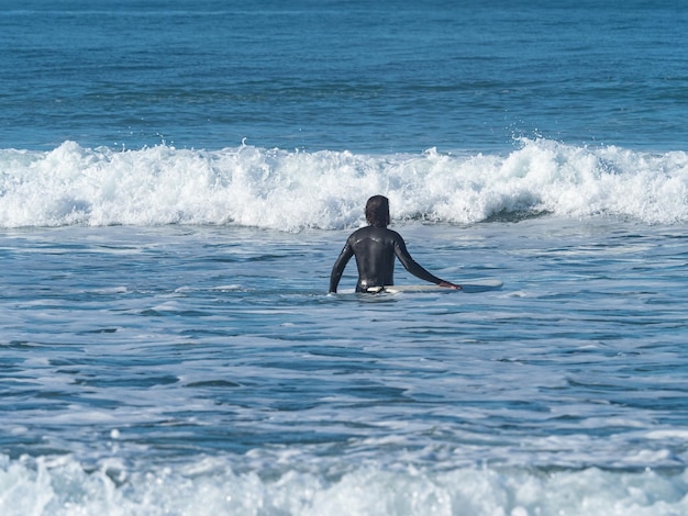 写真 海でサーフィンをしている男の後ろの景色