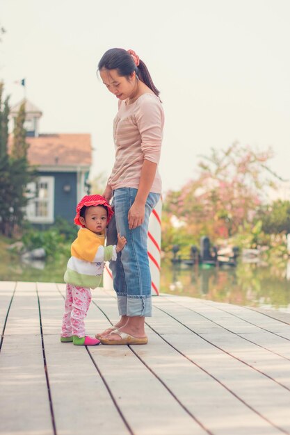 写真 明るい空に照らされて立っている母と娘の後ろの景色