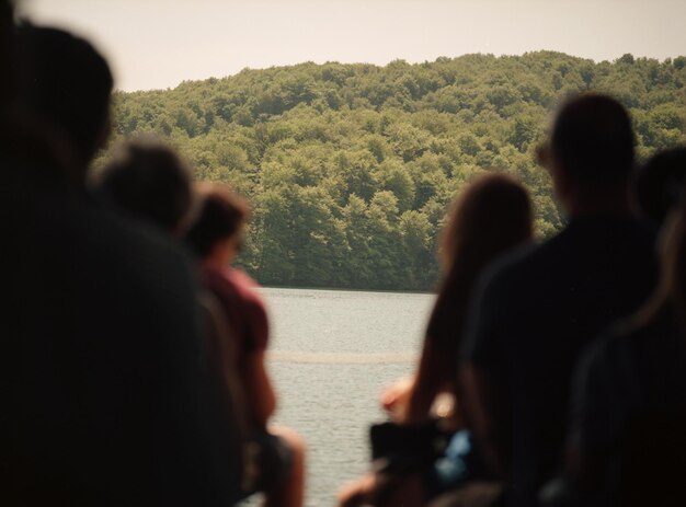 写真 山と空を背景に海を渡るボートに乗った人々の後ろの景色