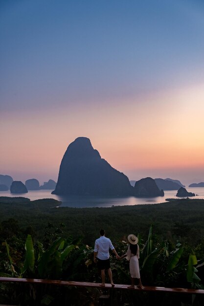 写真 夕暮れの空を背景に山を見ている人々の後ろの景色