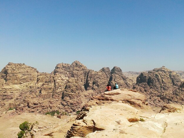 写真 ペトラの岩層に座っている人々の後ろの景色