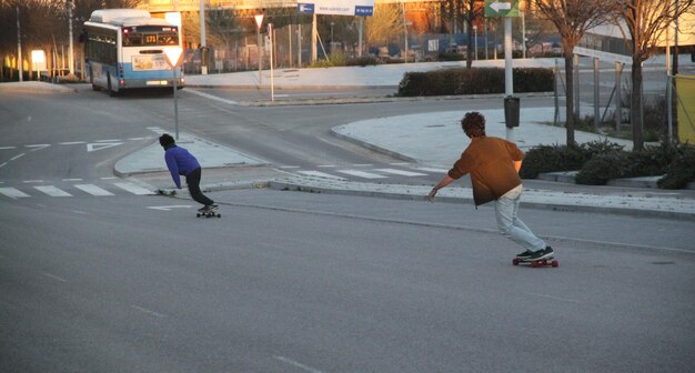 写真 街の通りでスケートをしている人々の後ろの景色