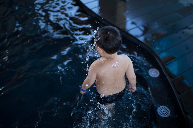 Фото Задний вид мальчика без рубашки, стоящего в бассейне