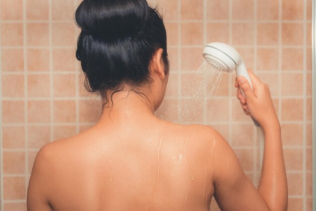 写真 バスルームでシャツを着ない女性がシャワーを浴びている後ろの景色