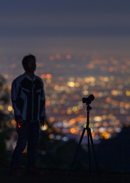 写真 夜空に逆らって立っているシルエットの男の後ろの景色