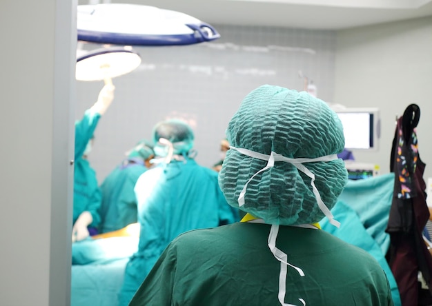 写真 手術室で働く同僚を見ている外科医の後ろの景色