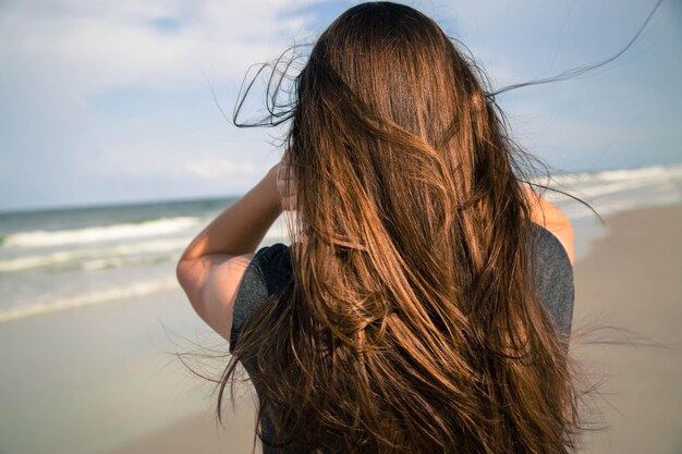 사진 하늘을 배경으로 해변에 서 있는 십대 소녀의 뒷면