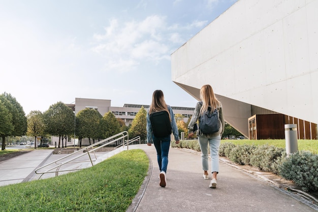 写真 話している間に一緒に大学を去る2人の大学のクラスメートの背面図。