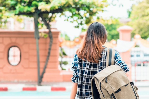 写真 外で立っている女性がバックパックを背負っている後ろの景色